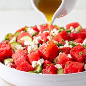Pouring dressing over Watermelon Feta Salad.