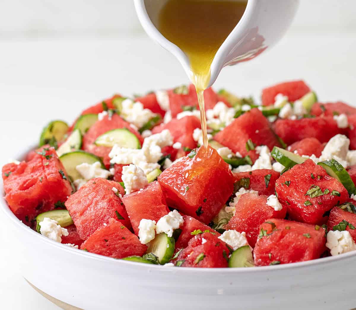 Pouring dressing over Watermelon Feta Salad.