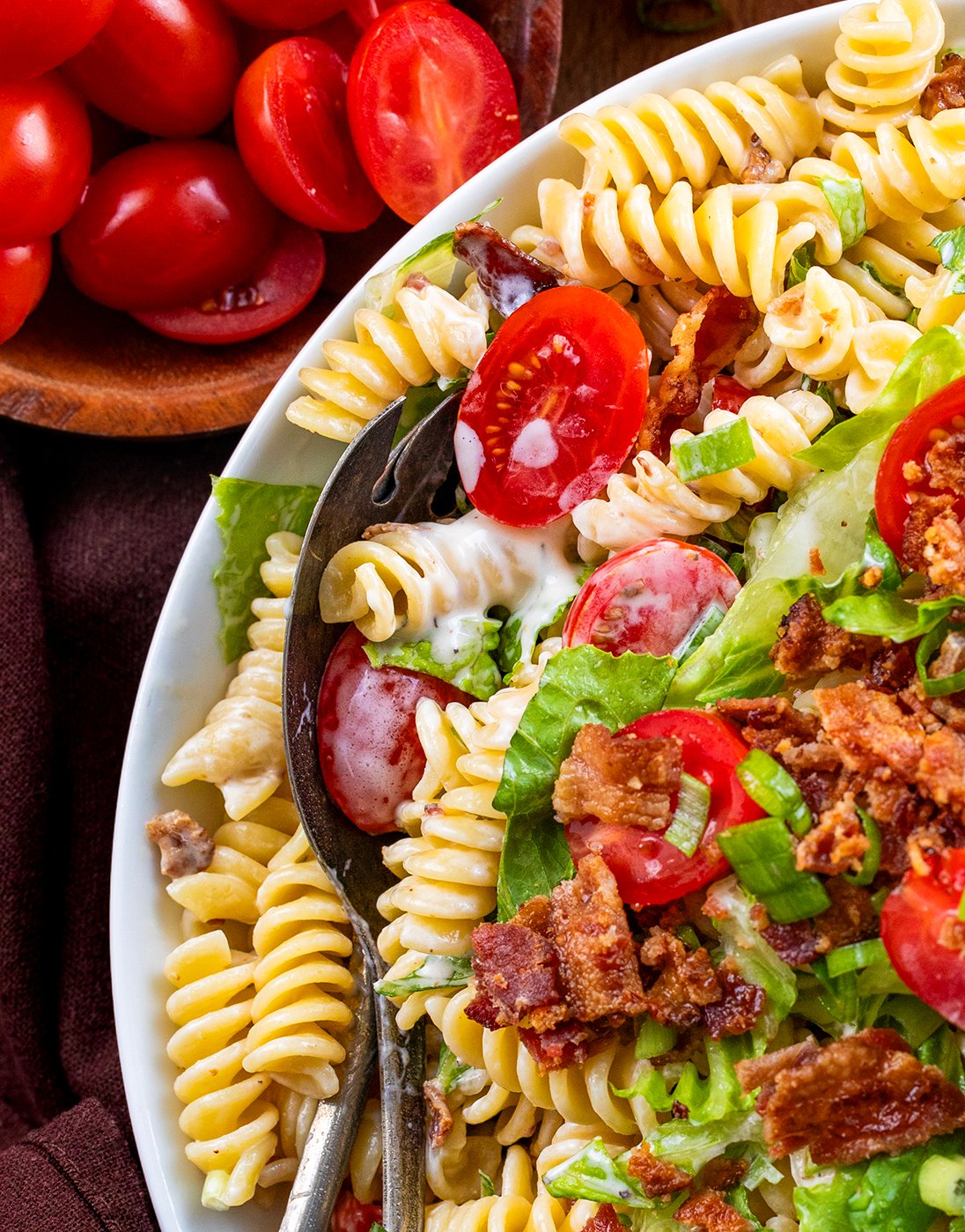 Close up of BLT Pasta Salad with dreaming saucy noodles and spoons in a bowl.