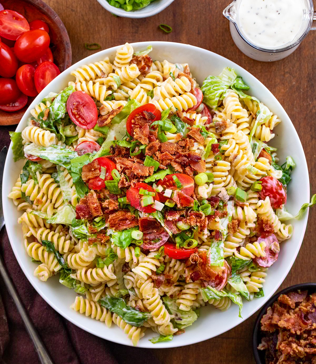 BLT Pasta Salad in a white bowl on a wooden table from overhead.
