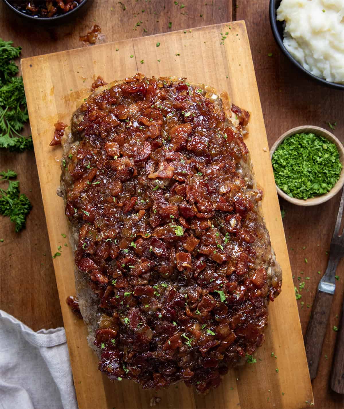 Bacon Jam Meatloaf on a cutting board with a bowl of bacon jam from overhead.