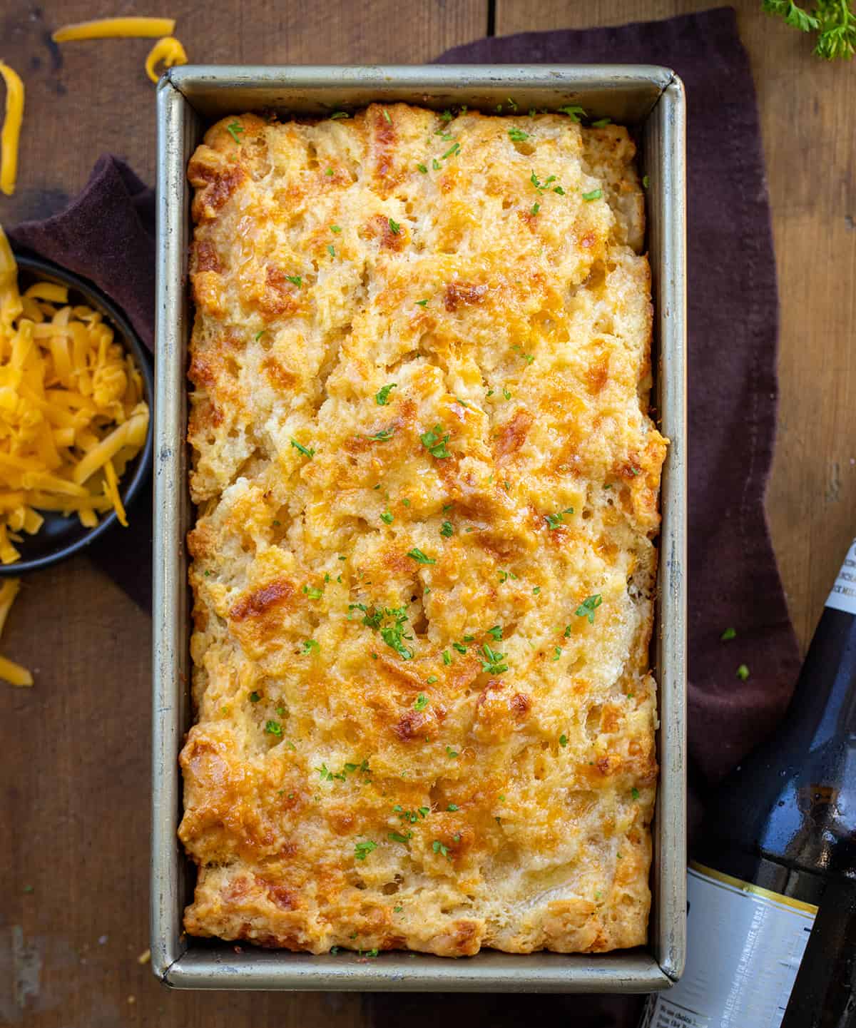 Beer Cheese Bread in a loaf pan on a wooden table from overhead. 