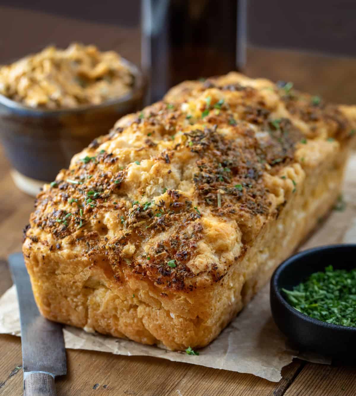 Loaf of Cowboy Butter Beer Bread on a wooden table with cowboy butter.