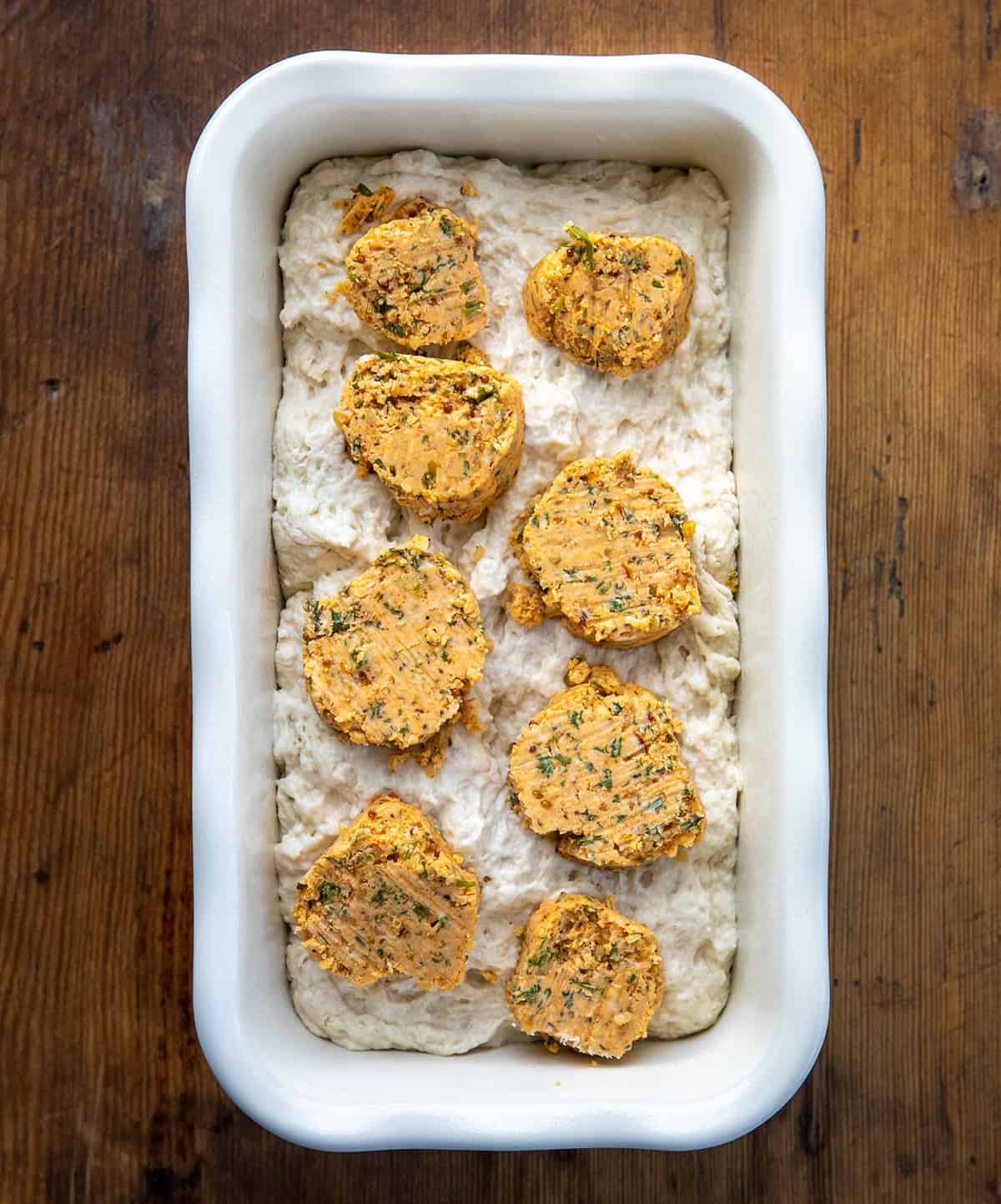 Raw batter with Cowboy Butter coins on it on a wooden table from overhead.