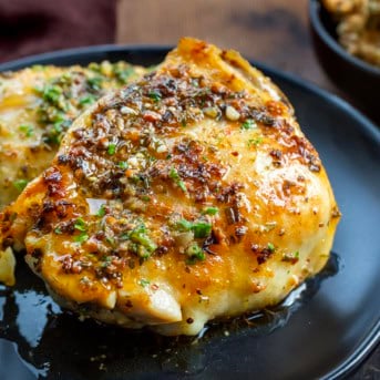 Cowboy Butter Chicken Thigh on a black plate on a wooden table.