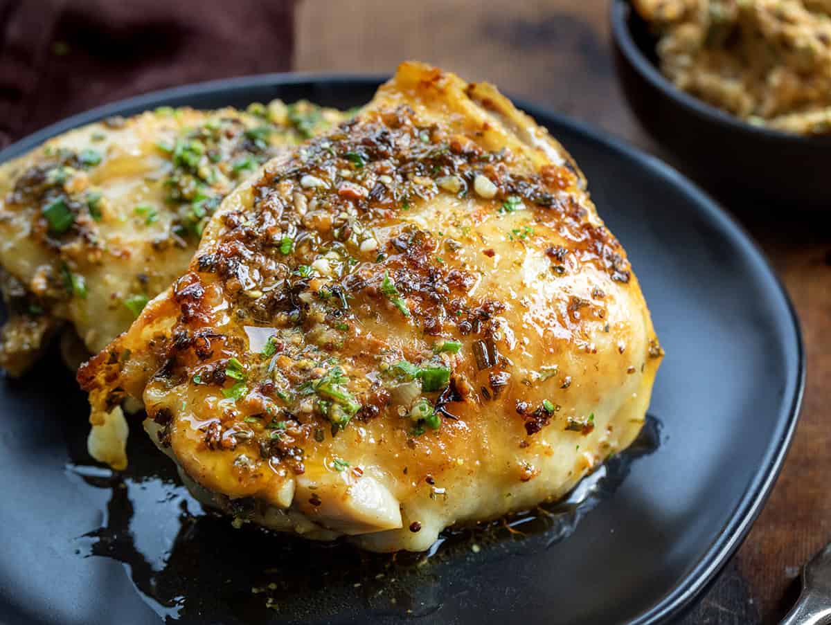 Cowboy Butter Chicken Thigh on a black plate on a wooden table.