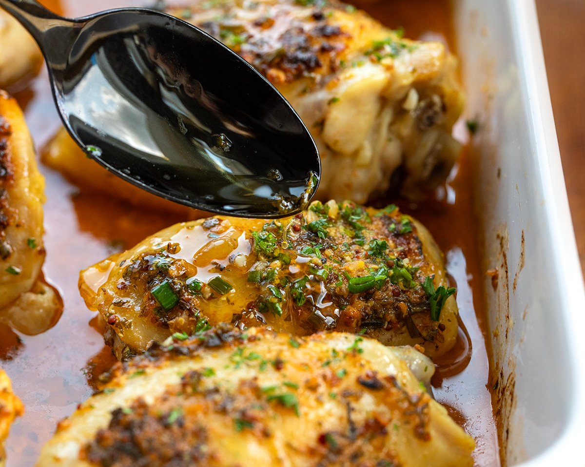 Drizzling cowboy butter over baked chicken thighs.