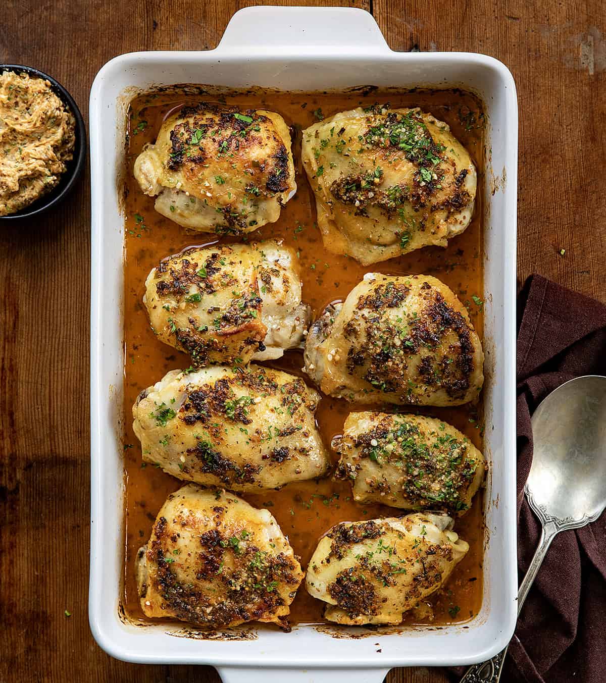 Cowboy Butter Chicken Thighs in a baking dish on a wooden table from overhead.