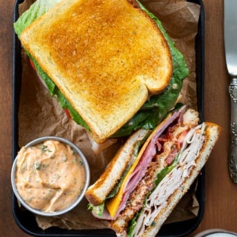 Cowboy Club Sandwiches on a tray with a bowl of cowboy mayo.