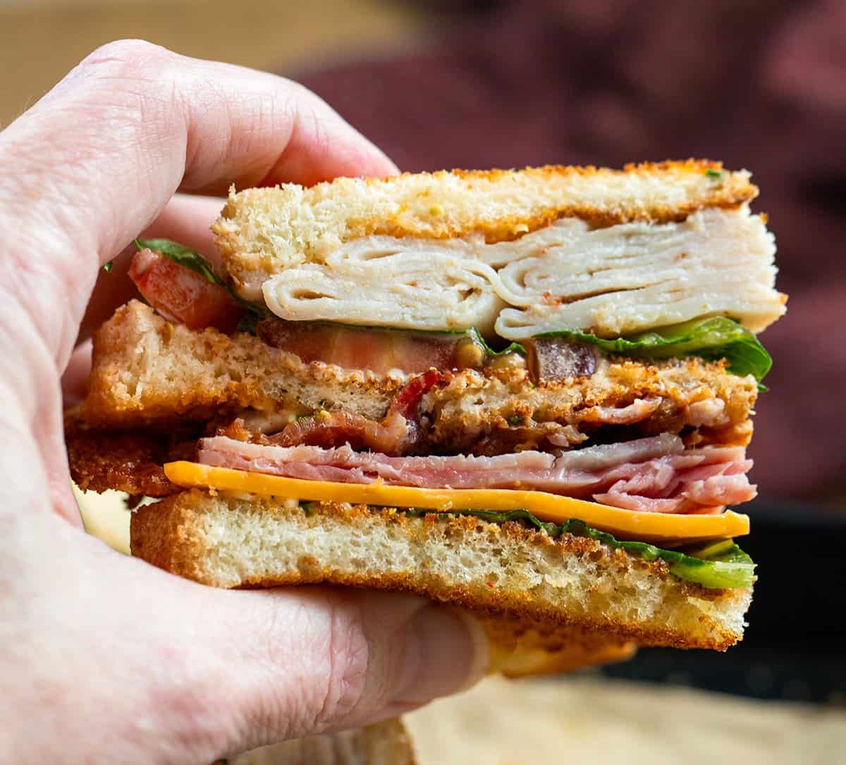 Hand holding a quarter of a Cowboy Club Sandwich.