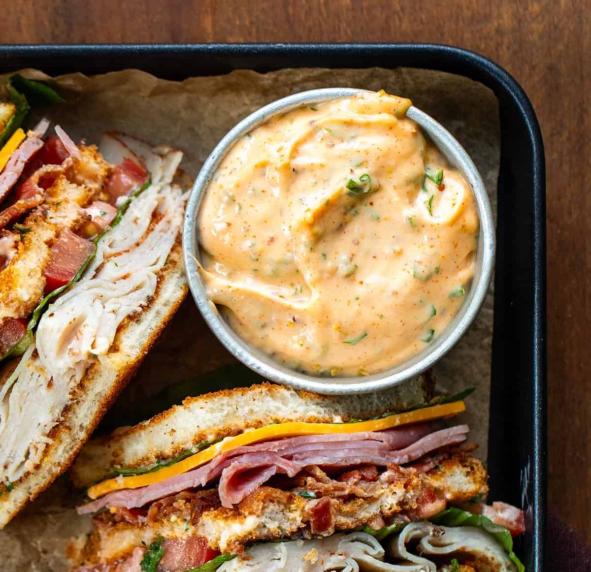 Close up of a bowl of Cowboy Mayo next to Cowboy Club Sandwiches.
