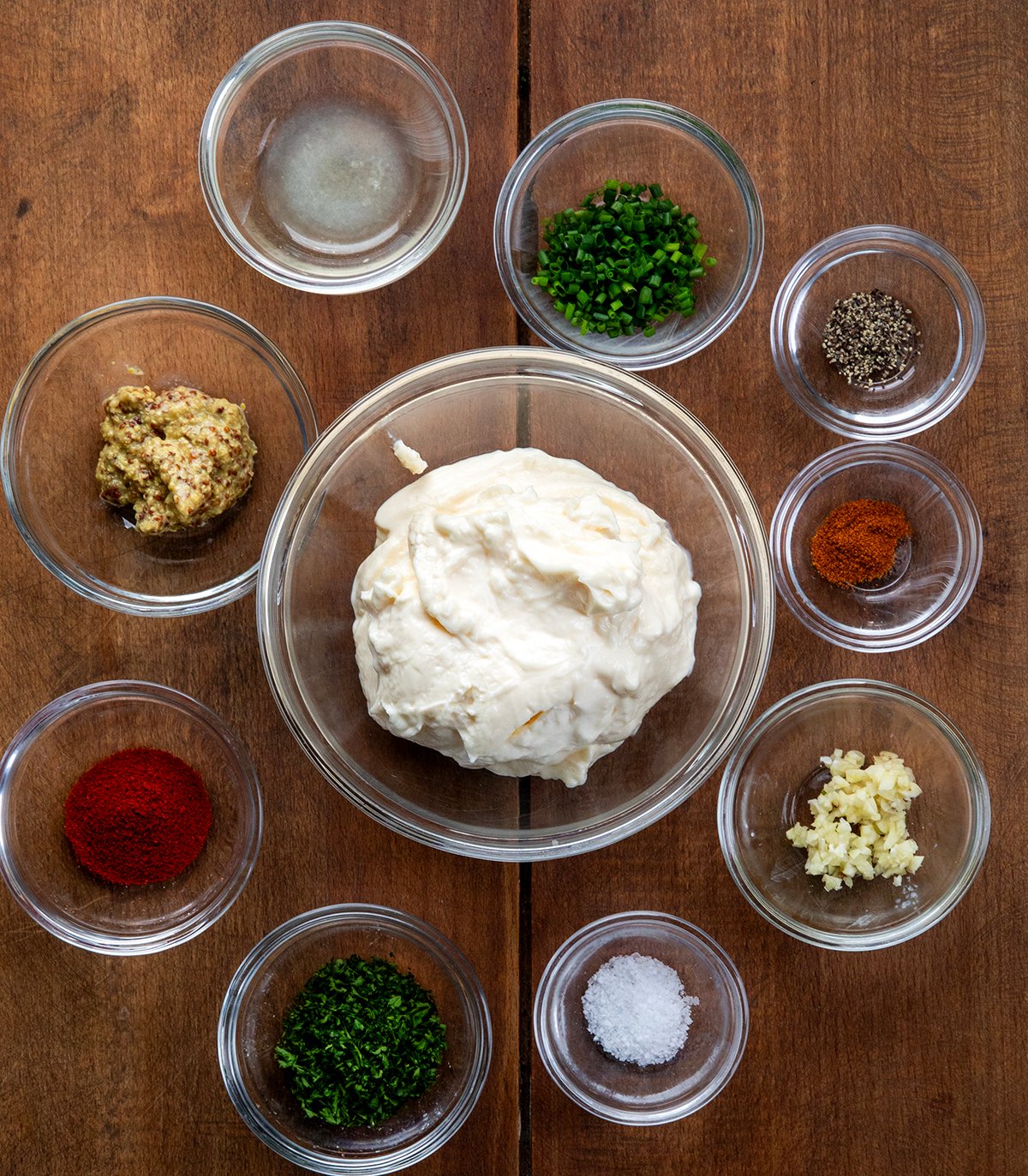Ingredients for Cowboy Mayo in glass bowls on a wooden table from overhead.