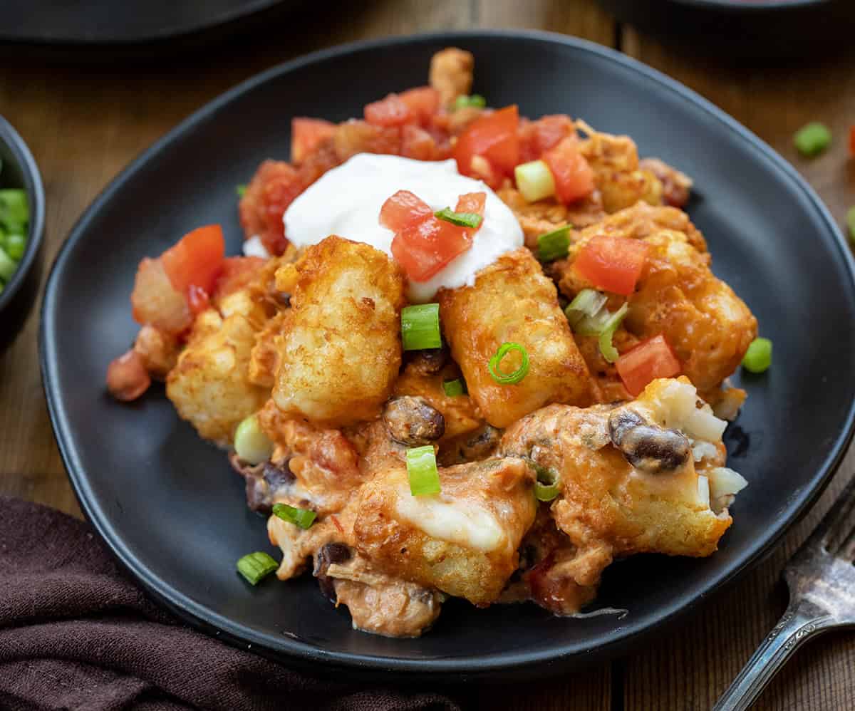 Fiesta Chicken Tater Tot Casserole on a black plate on a wooden table.