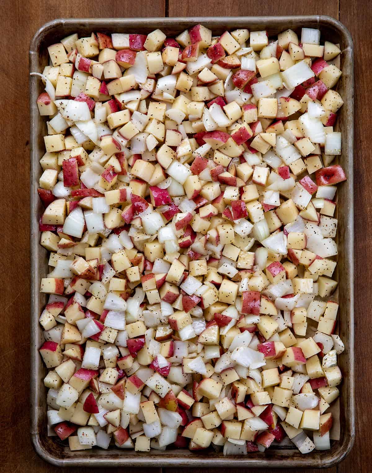 French Onion Roasted Potatoes before being roasted on a sheet pan on a wooden table.