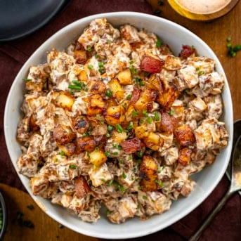 Bowl of French Onion Roasted Potato Salad on a wooden table from overhead.