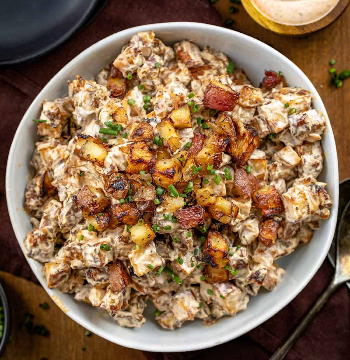 Bowl of French Onion Roasted Potato Salad on a wooden table from overhead.