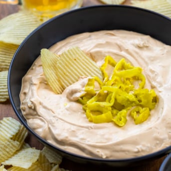 Bowl of Mississippi Pot Roast Dip with a couple of chips in it.