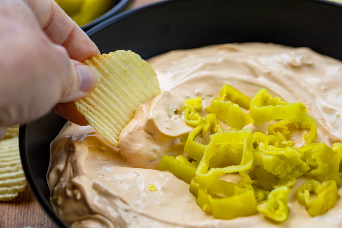 Hand dipping a chip into Mississippi Pot Roast Dip.