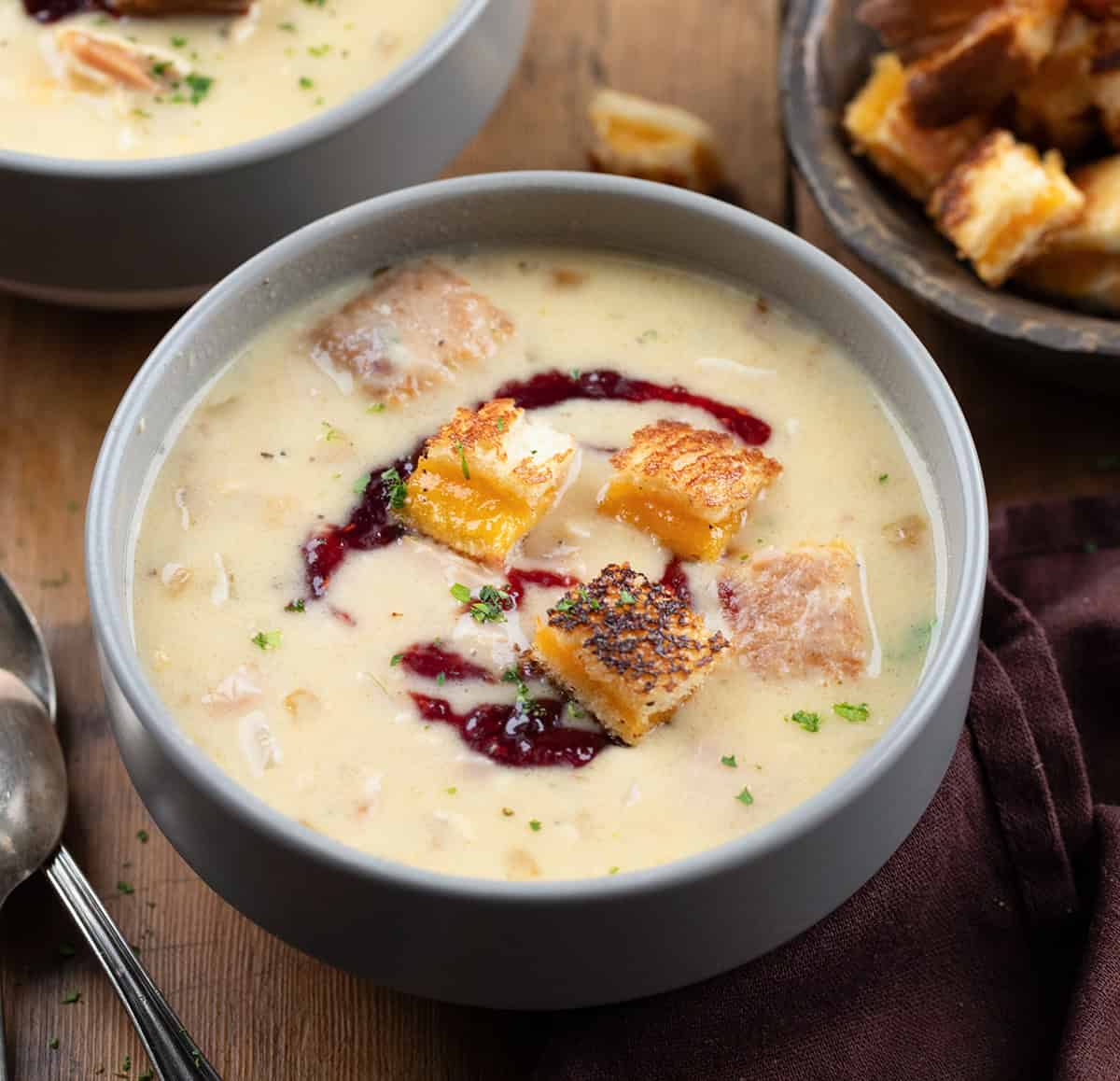 Bowl of Monte Cristo Soup on a wooden table next to grilled cheese croutons.
