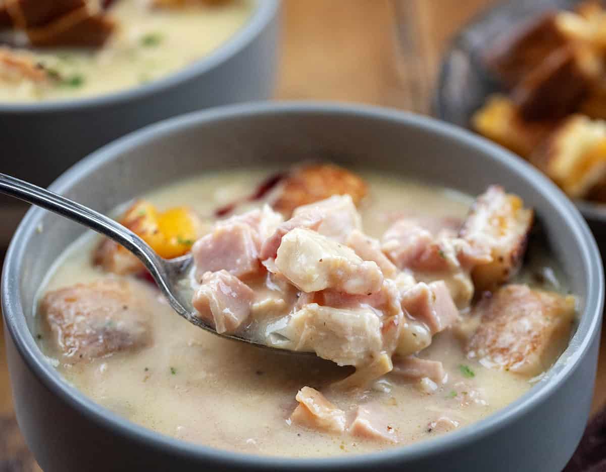 Spoonful of creamy Monte Cristo Soup being held above the bowl.