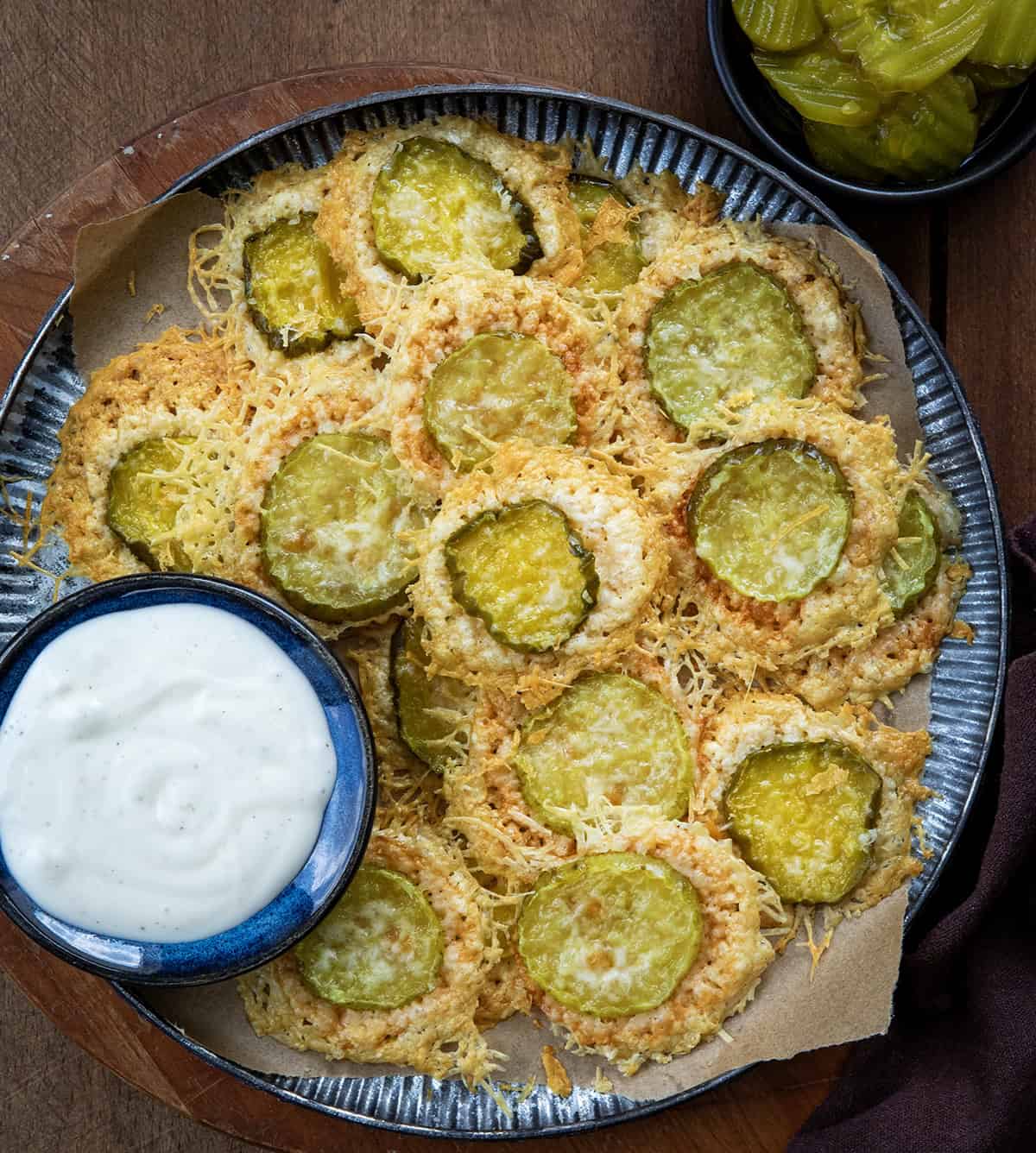 Platter of Parmesan Pickle Crisps on a wooden table from overhead.