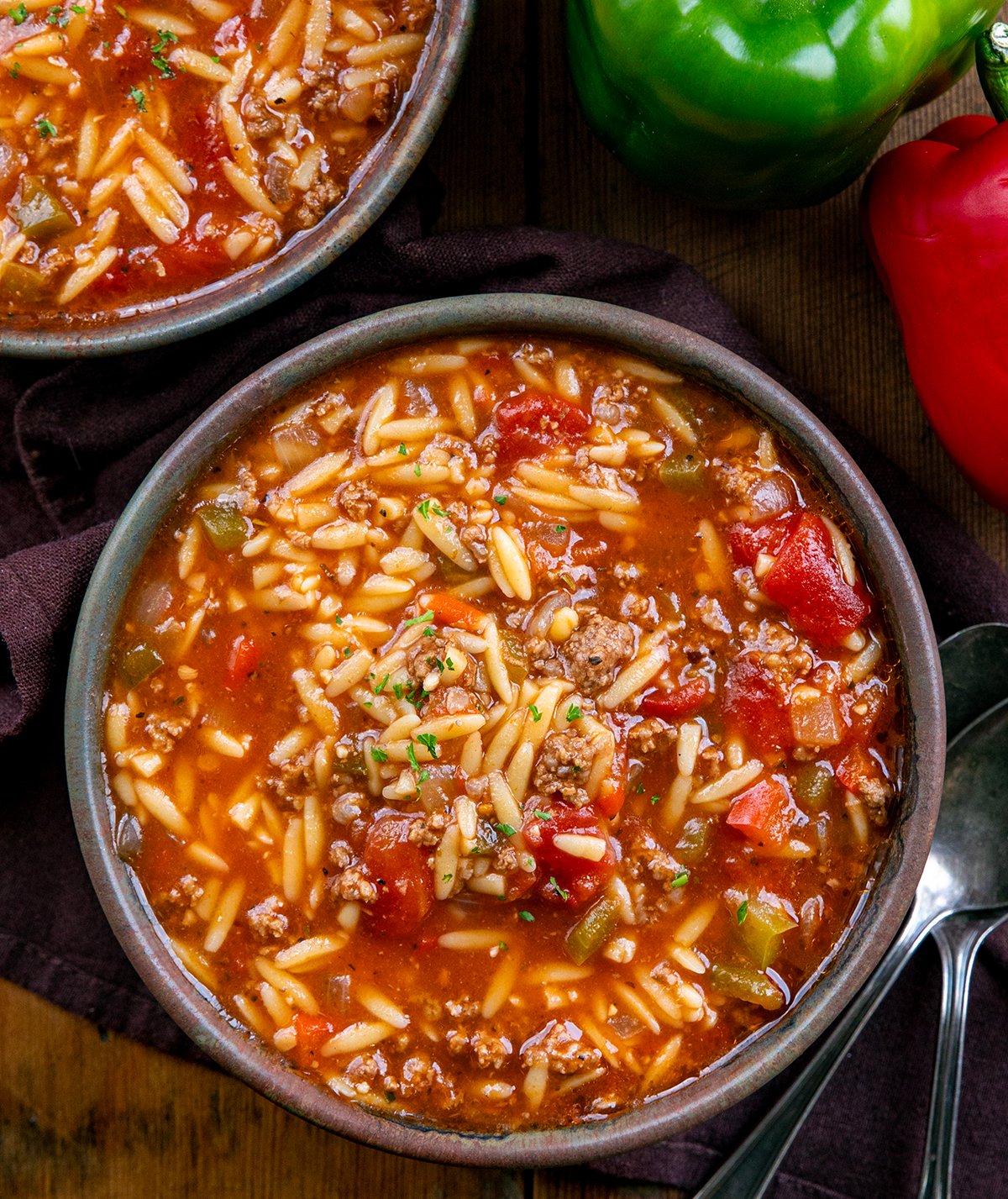 Bowls of Stuffed Pepper Orzo Soup on a wooden table from overhead.