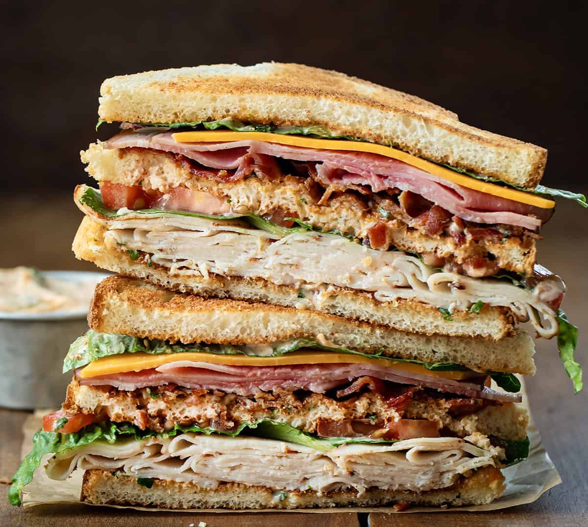 Cut in half and stacked Cowboy Club Sandwiches on a wooden table.