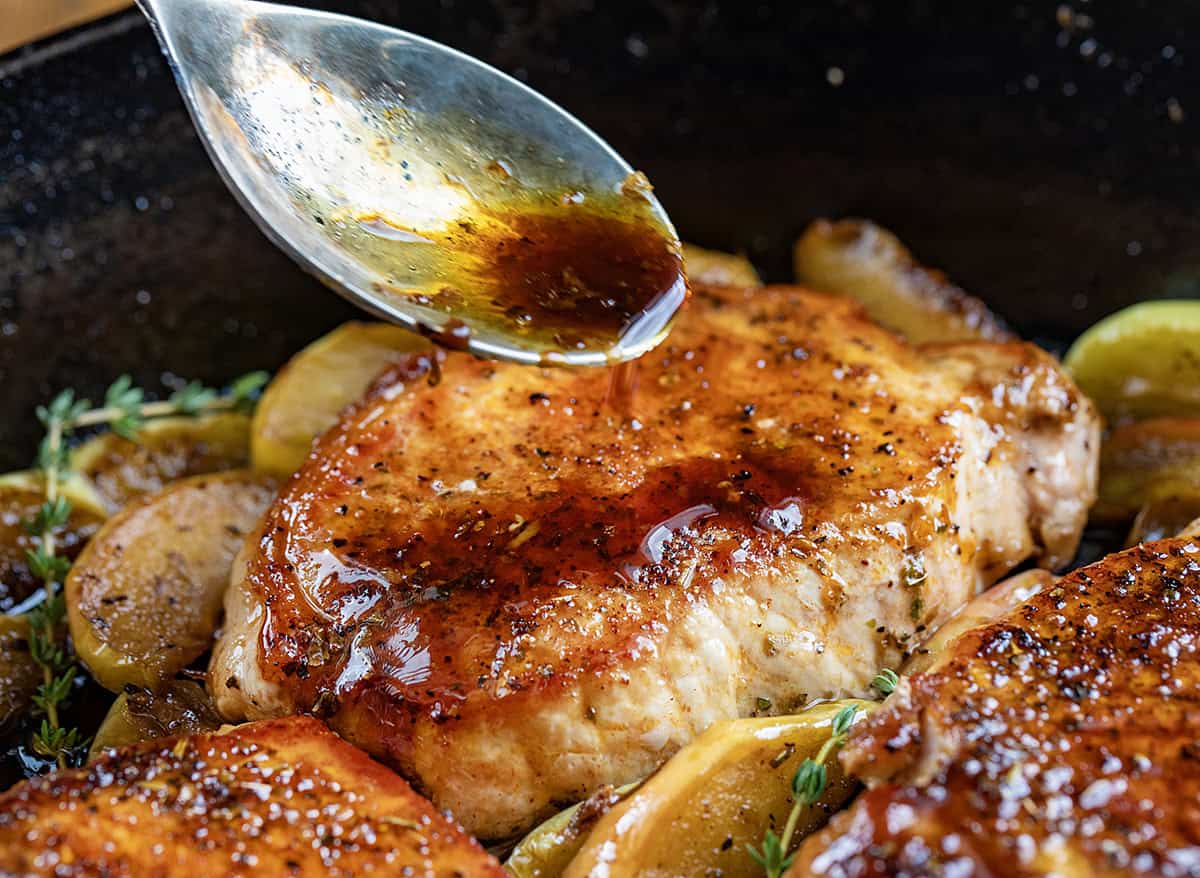 Drizzling apple cider sauce over pork chops.