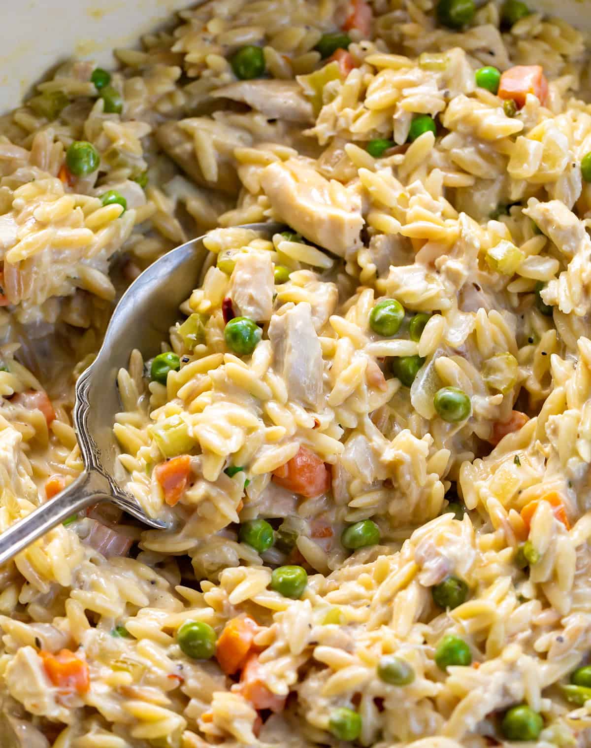 Spoon nestled in a pot of Chicken Pot Pie Orzo.