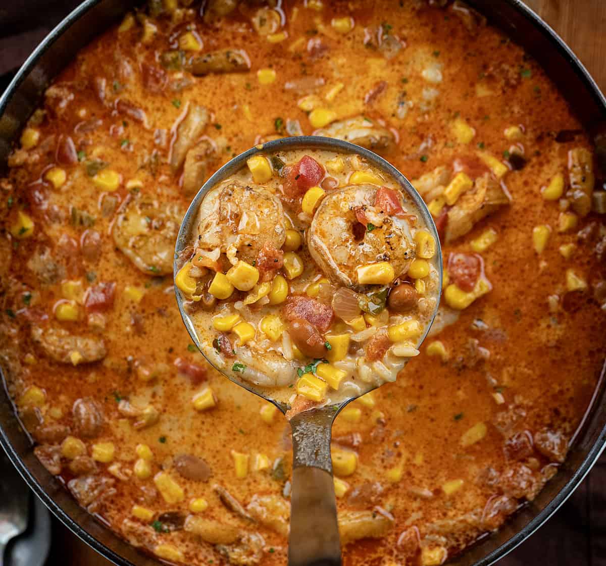 Ladle full of Chipotle Shrimp Soup being held above the pot.
