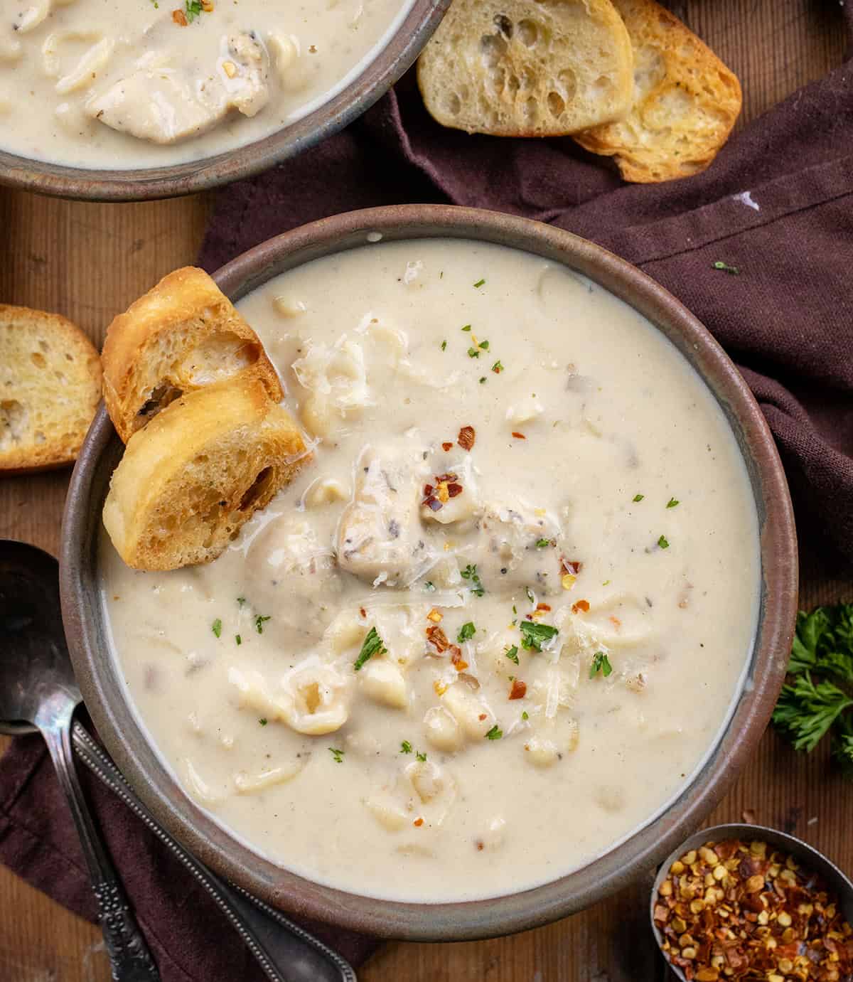 Bowls of Garlic Parmesan Chicken Chowder on a wooden table from overhead.
