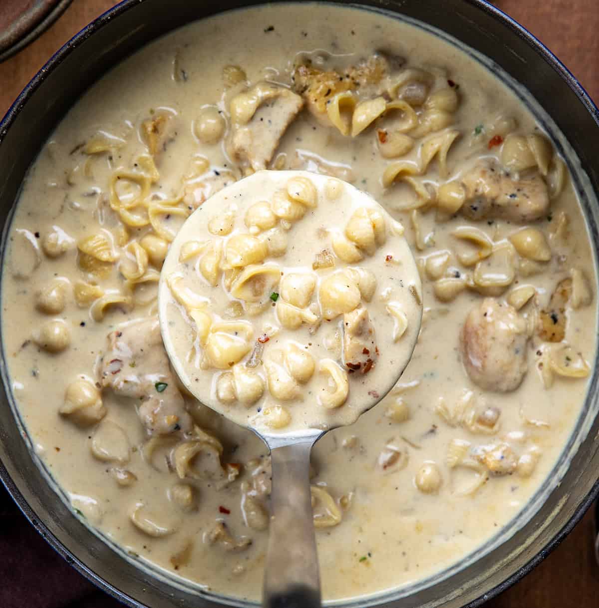 Holding a ladle of Garlic Parmesan Chicken Chowder over the pot.