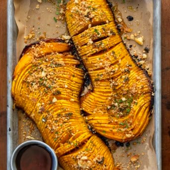 Hasselback Butternut Squash on a sheet pan on a wooden table from overhead.