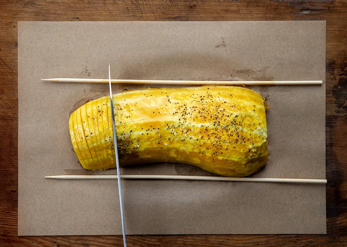 Image with a knife and chopsticks showing how to thinly slice Hasselback Butternut Squash.