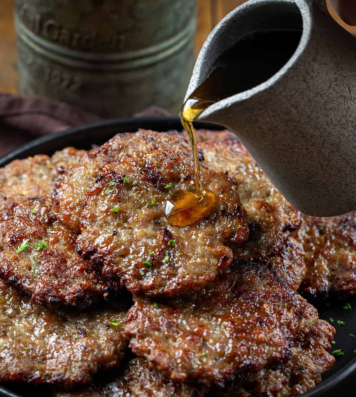 Pouring syrup over breakfast sausage patties.