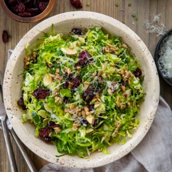 Bowl of Shaved Brussels Sprout Salad on a wooden table from overhead.