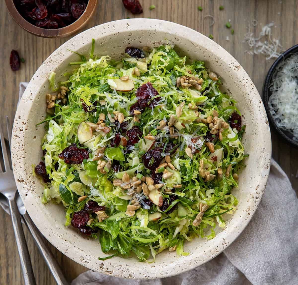 Bowl of Shaved Brussels Sprout Salad on a wooden table from overhead. 