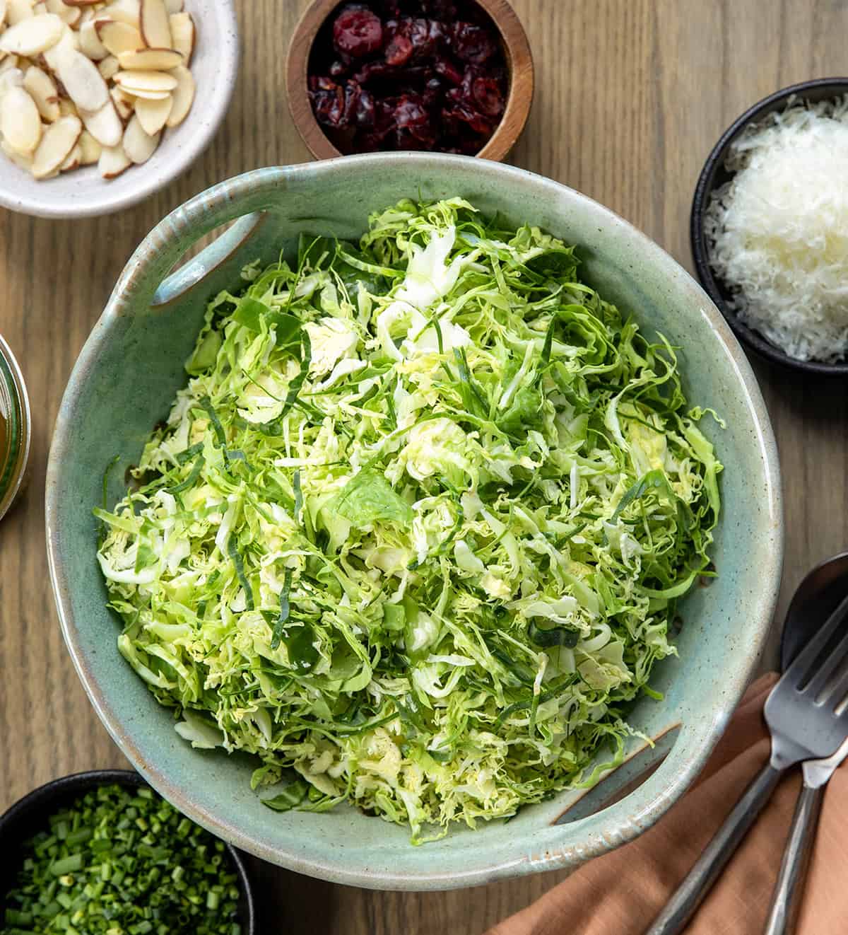 Raw ingredients for Shaved Brussels Sprout Salad before being combined on a wooden table from overhead.