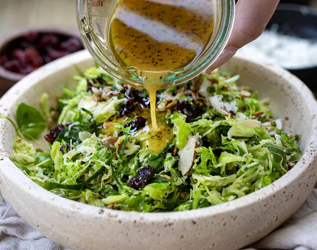 Pouring dressing over Shaved Brussels Sprout Salad.