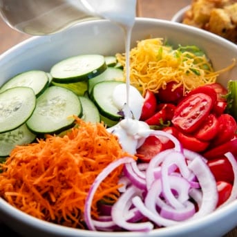 Pouring ranch dressing over a Simple Side Salad.