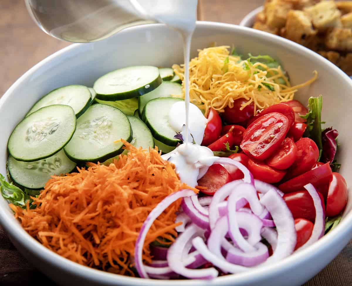 Pouring ranch dressing over a Simple Side Salad.
