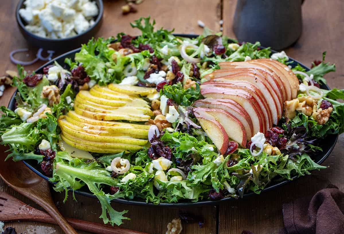 Black platter of Winter Pear Salad on a wooden table.