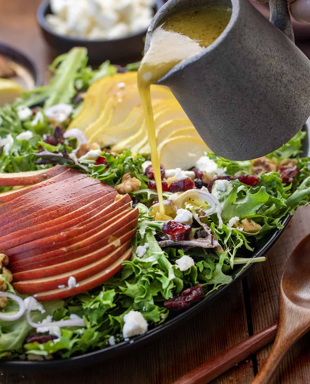 Pouring dressing over a Winter Pear Salad.