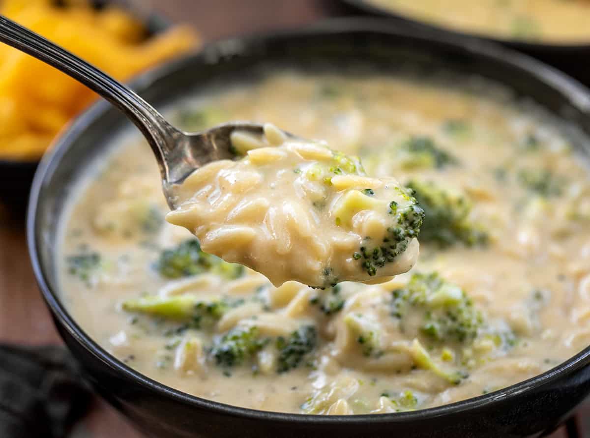 Spoonful of Broccoli Cheddar Orzo Soup held above the bowl.