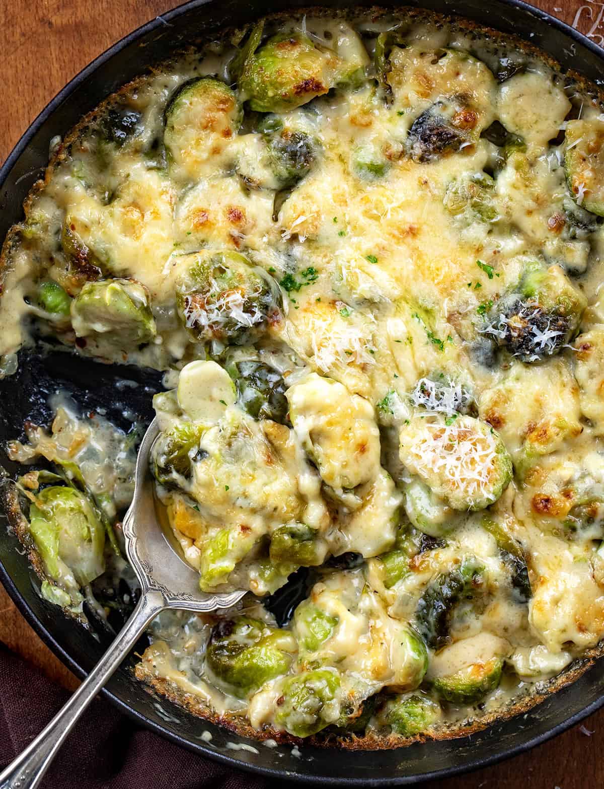 Spoon resting in a skillet of Brussels Sprouts Gratin.