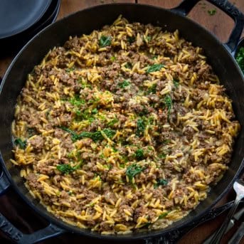 Skillet of Cheesy Beef Orzo on a wooden table from overhead.