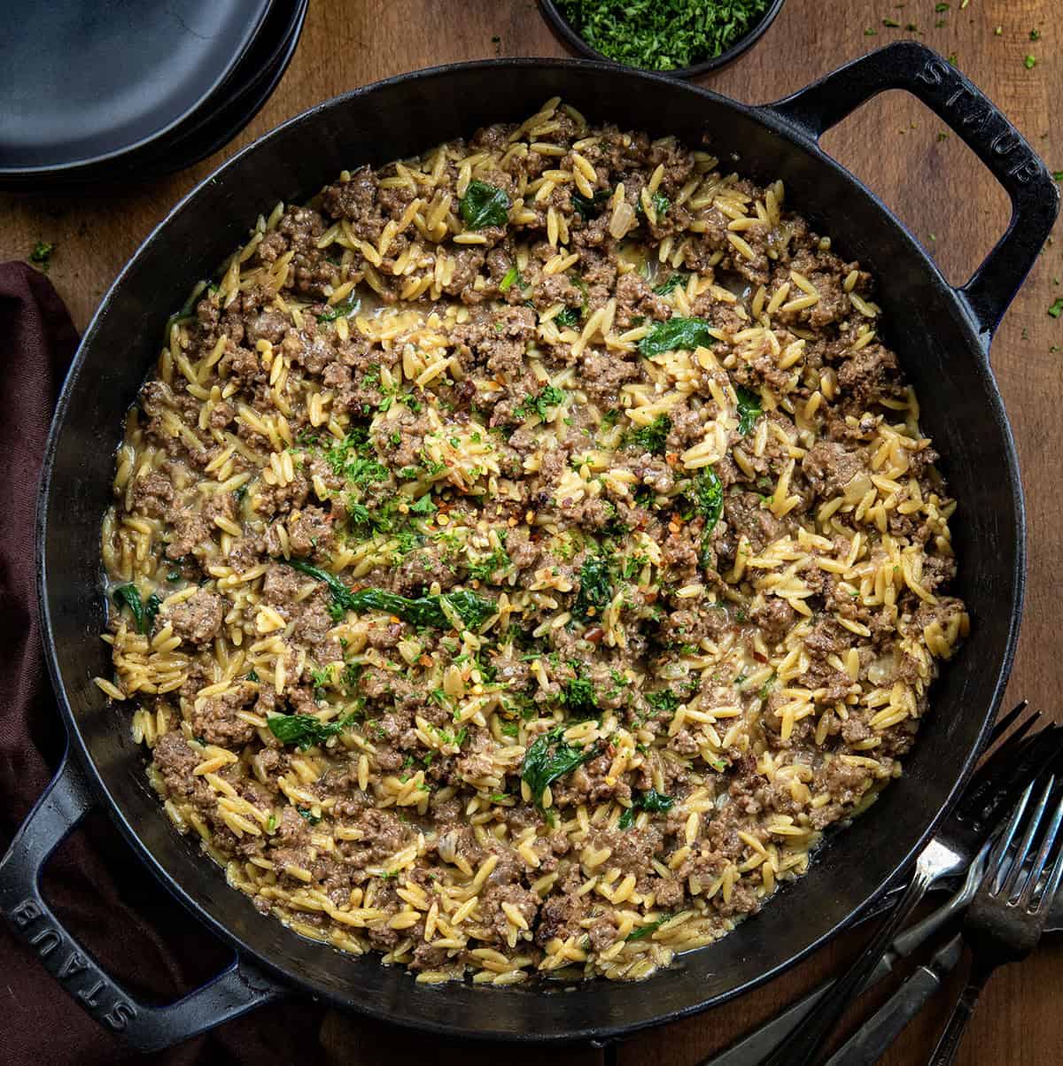 Skillet of Cheesy Beef Orzo on a wooden table from overhead.