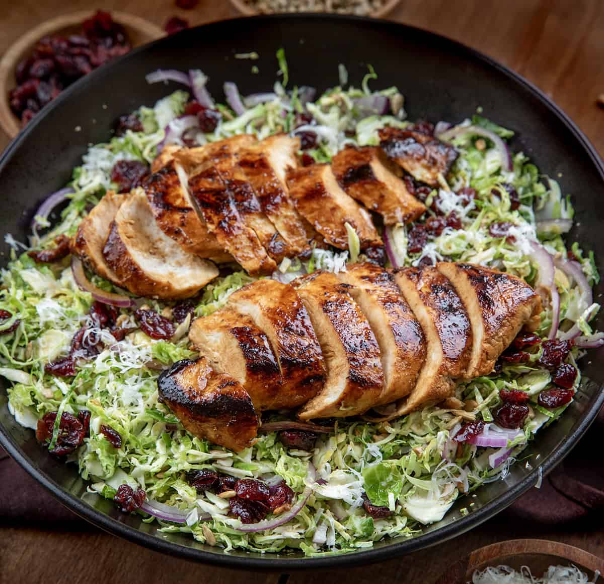 Black salad bowl filled with Chicken Brussels Sprout Salad on a wooden table.