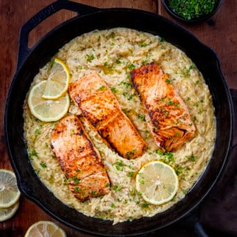 Skillet of Creamy Lemon Orzo with Salmon on a wooden table from overhead.