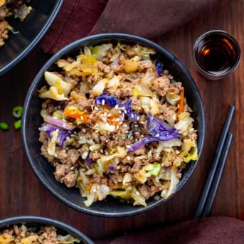 Black bowls filled with Egg Roll In A Bowl on a wooden table from overhead.